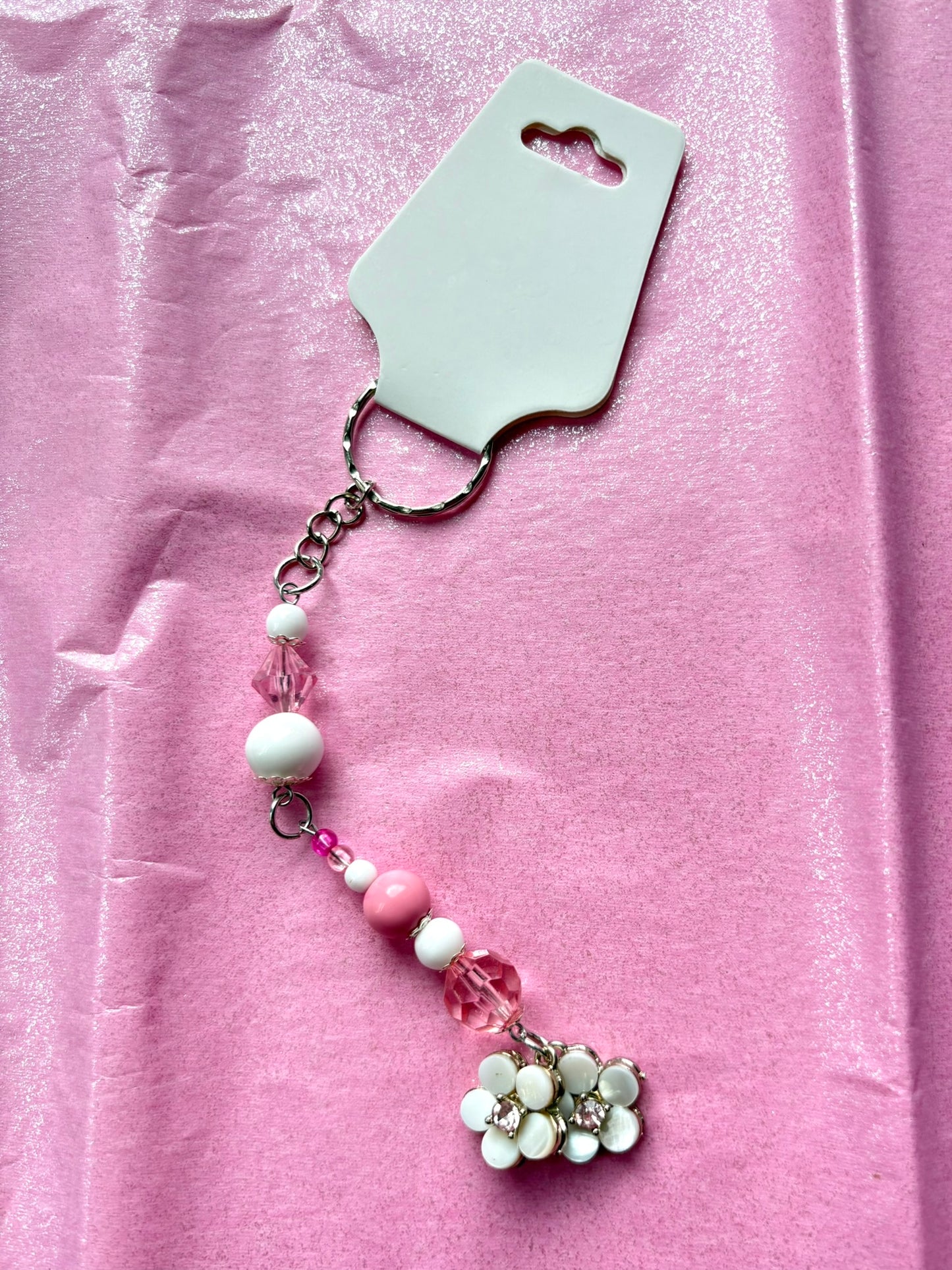 Decorative keychain with beads and a flower charm on a pink background