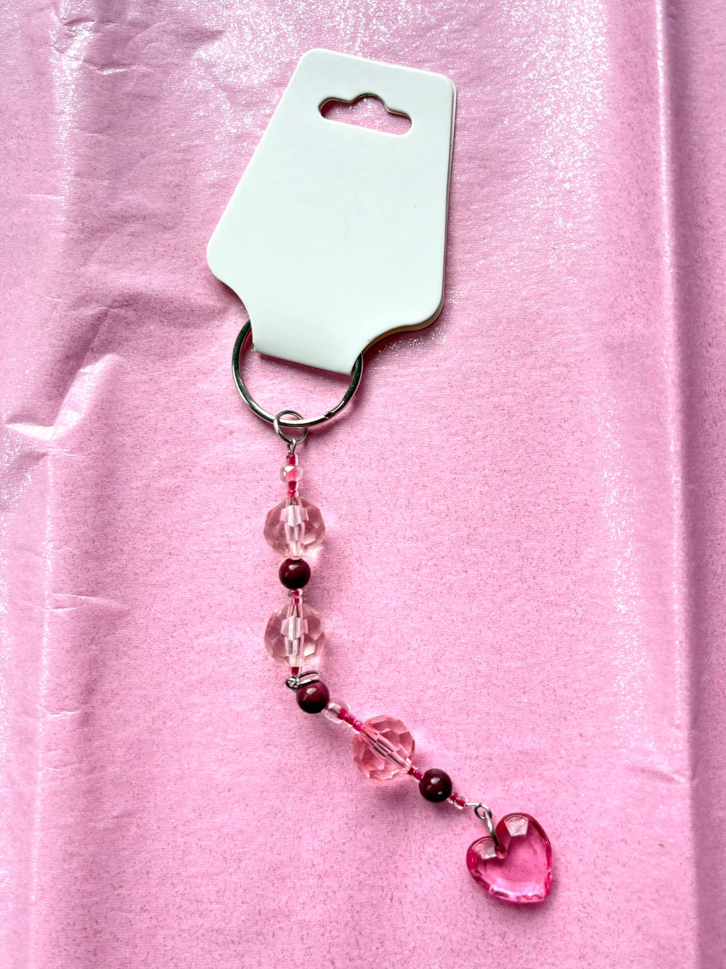 Pink beaded keychain with heart charm on a pink background