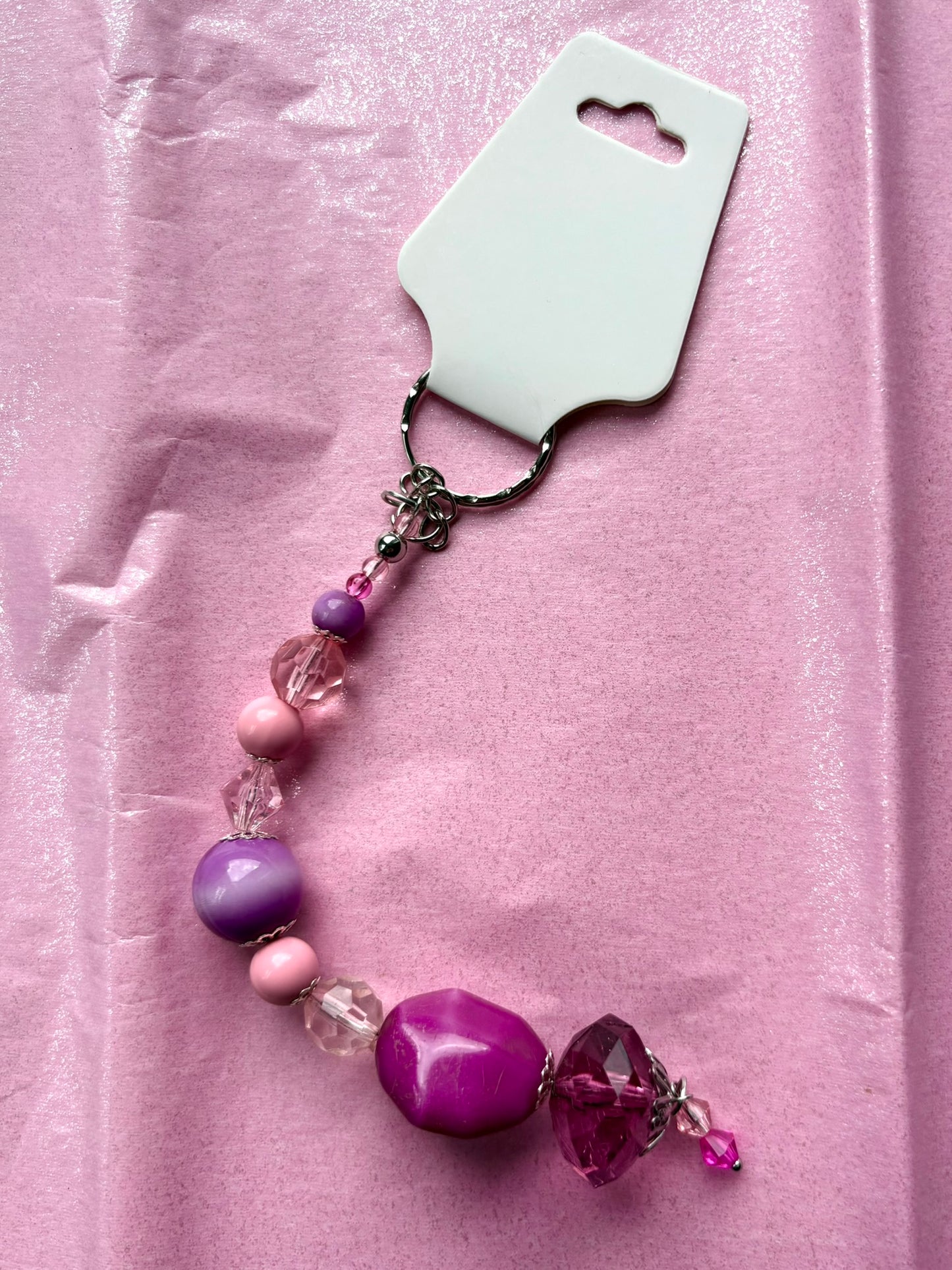 Beaded keychain with purple and pink beads on a pink background
