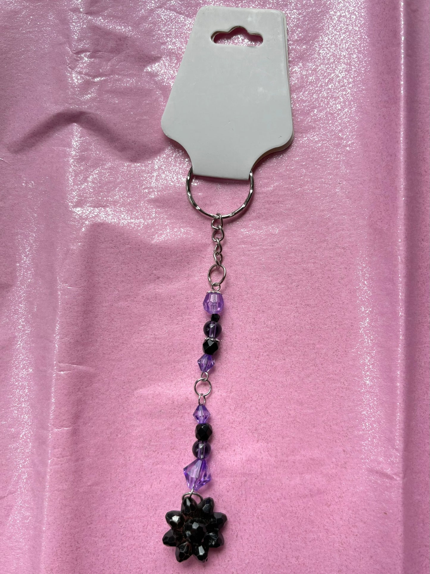 Keychain with beads and a flower charm on a pink background