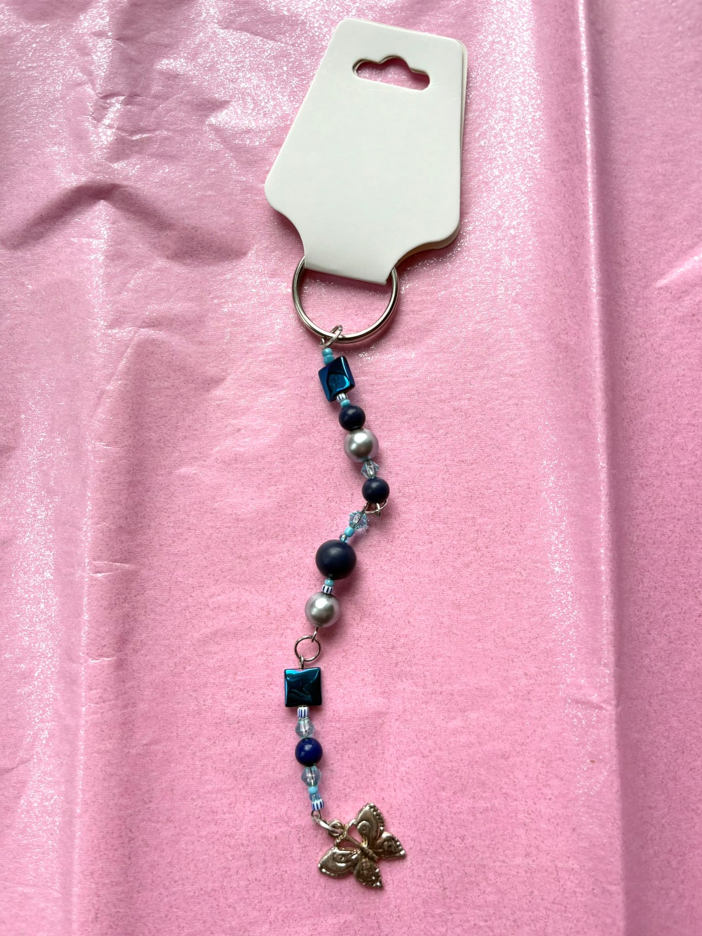 Beaded keychain with a butterfly charm on a pink background