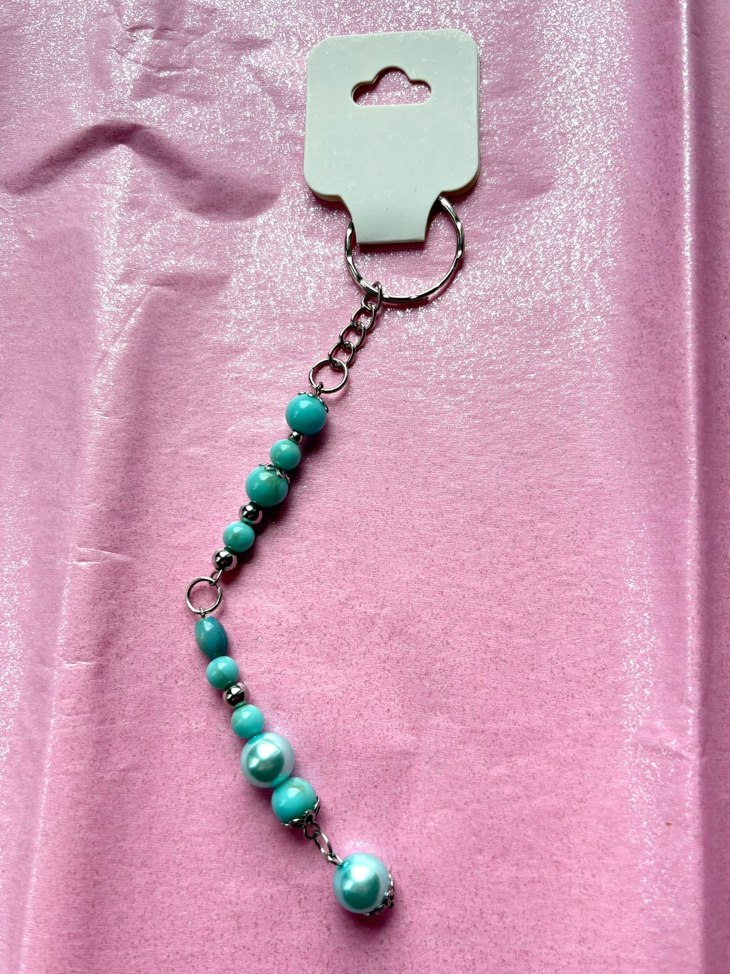Turquoise beaded keychain on a pink background