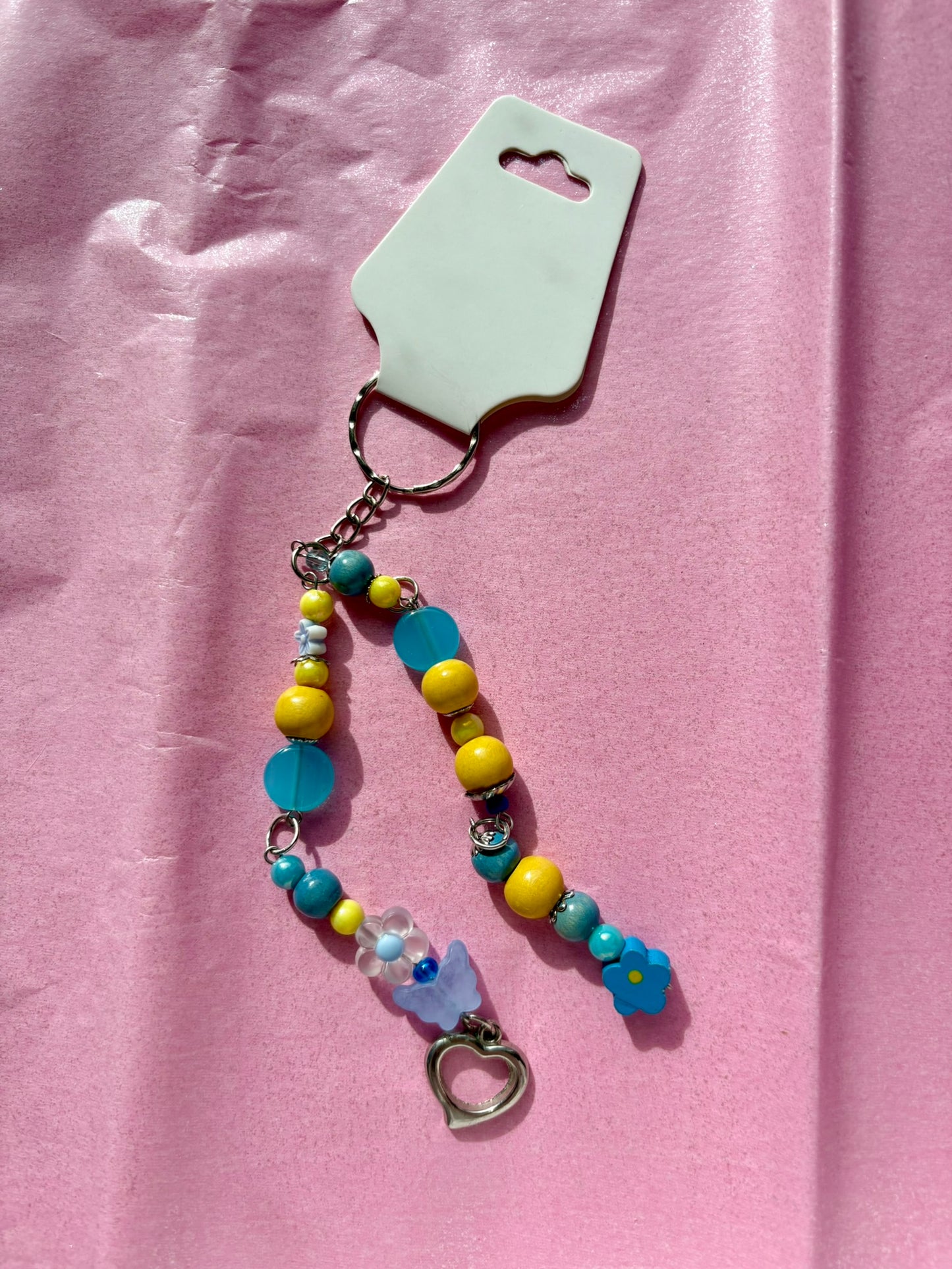 Colorful beaded keychain with a heart charm on a pink background