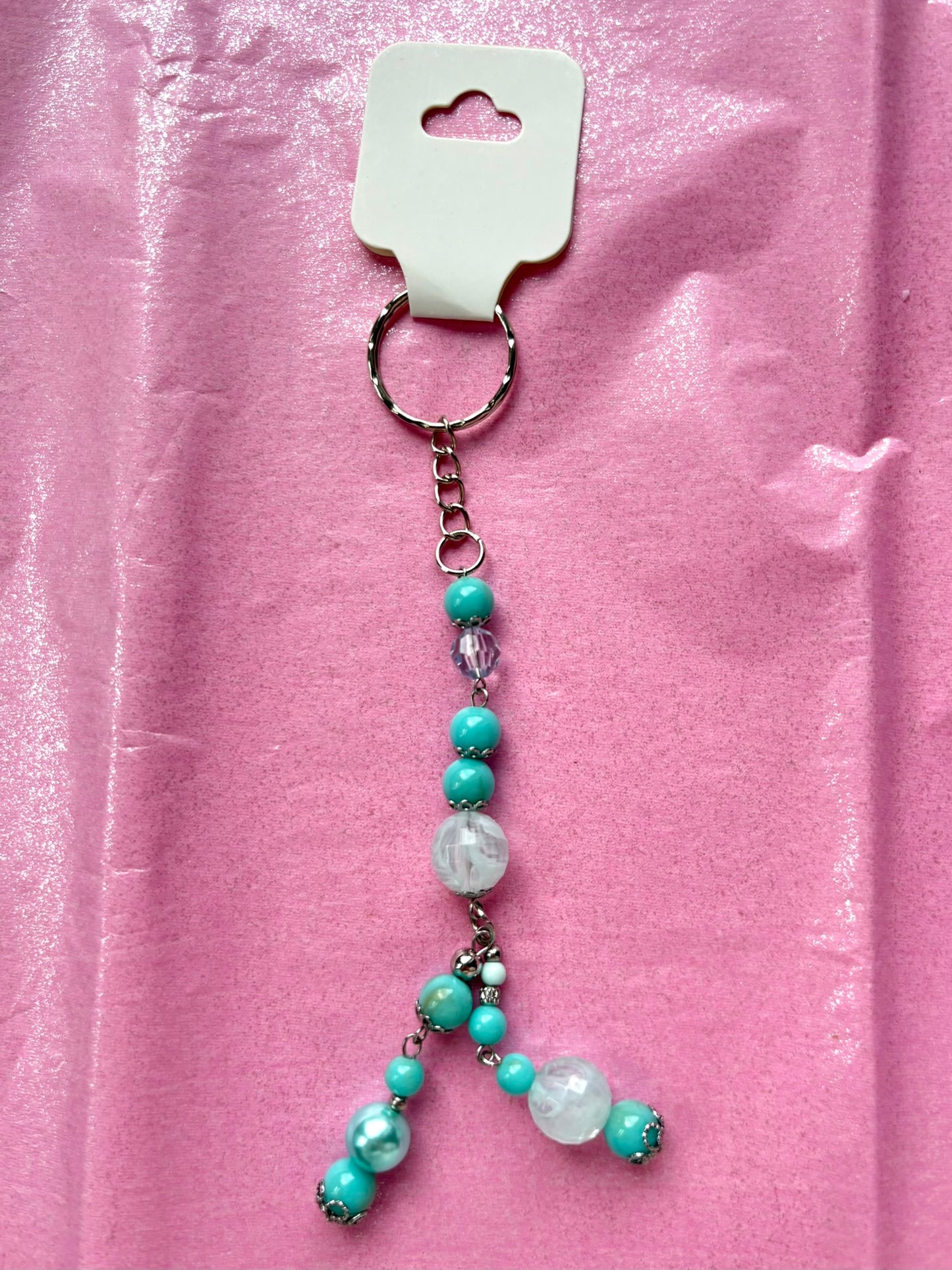 Beaded keychain with turquoise and white beads on a pink background