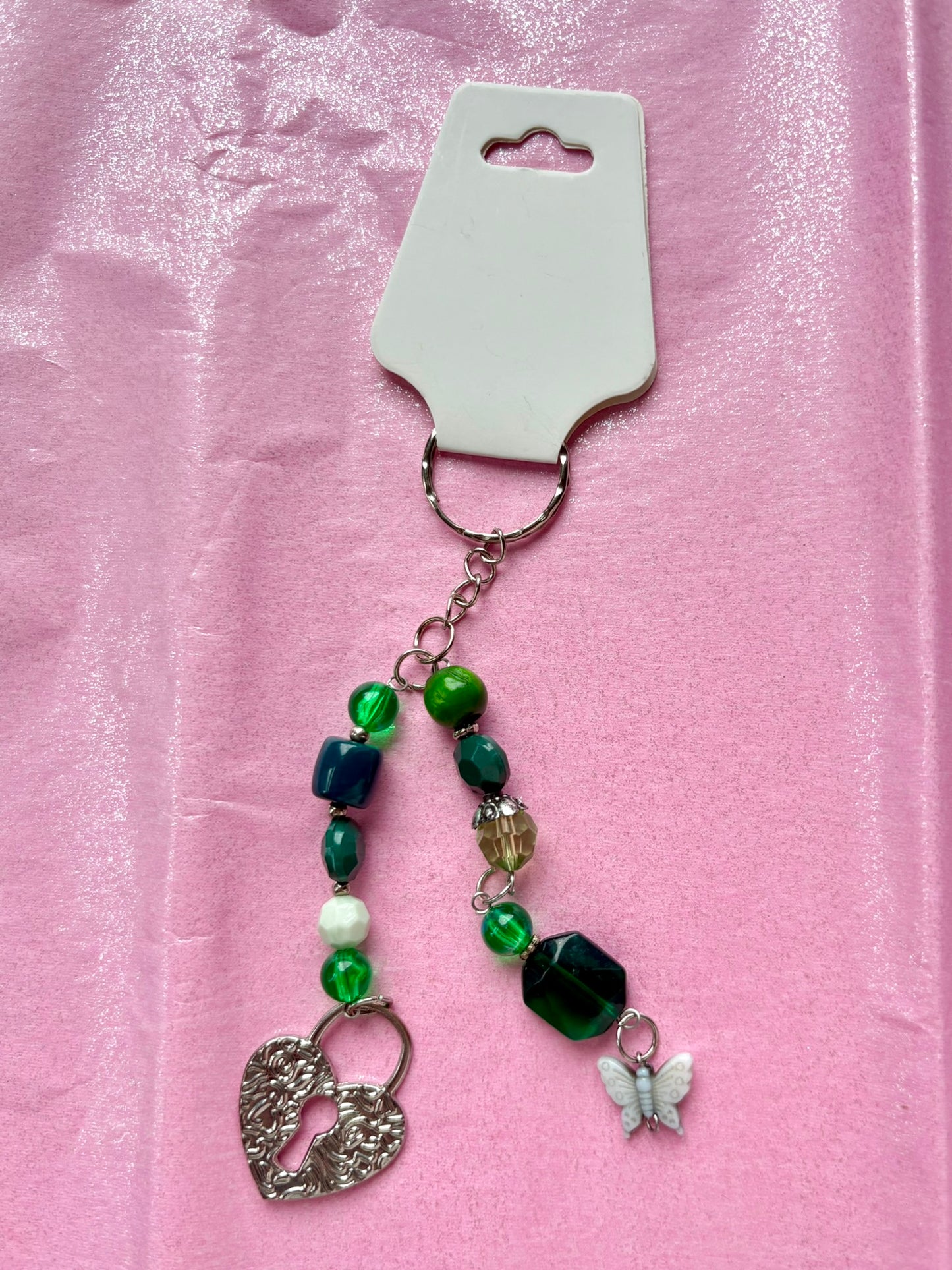 Keychain with green beads and charms on a pink background