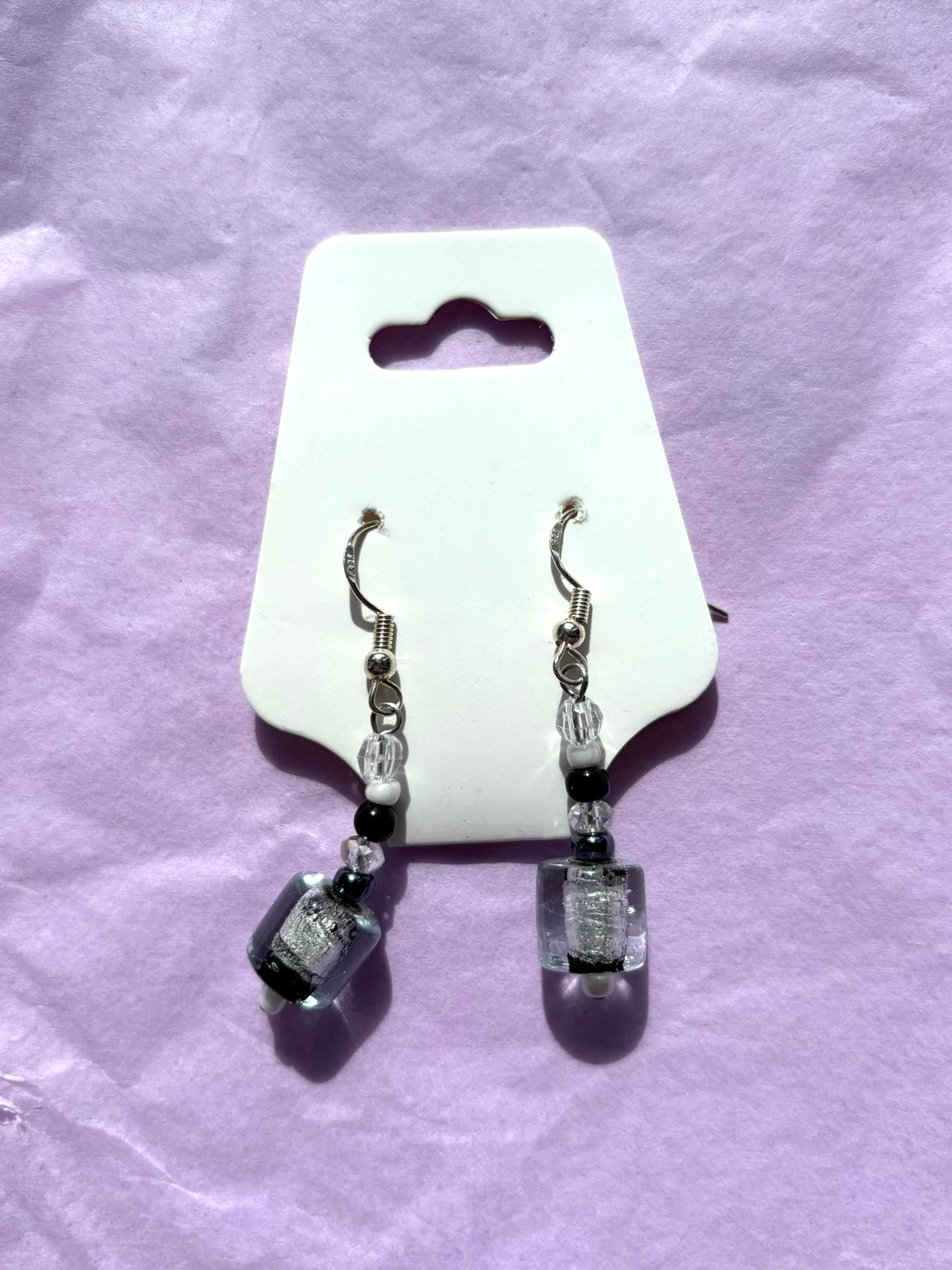 Pair of earrings on a white card with a purple background