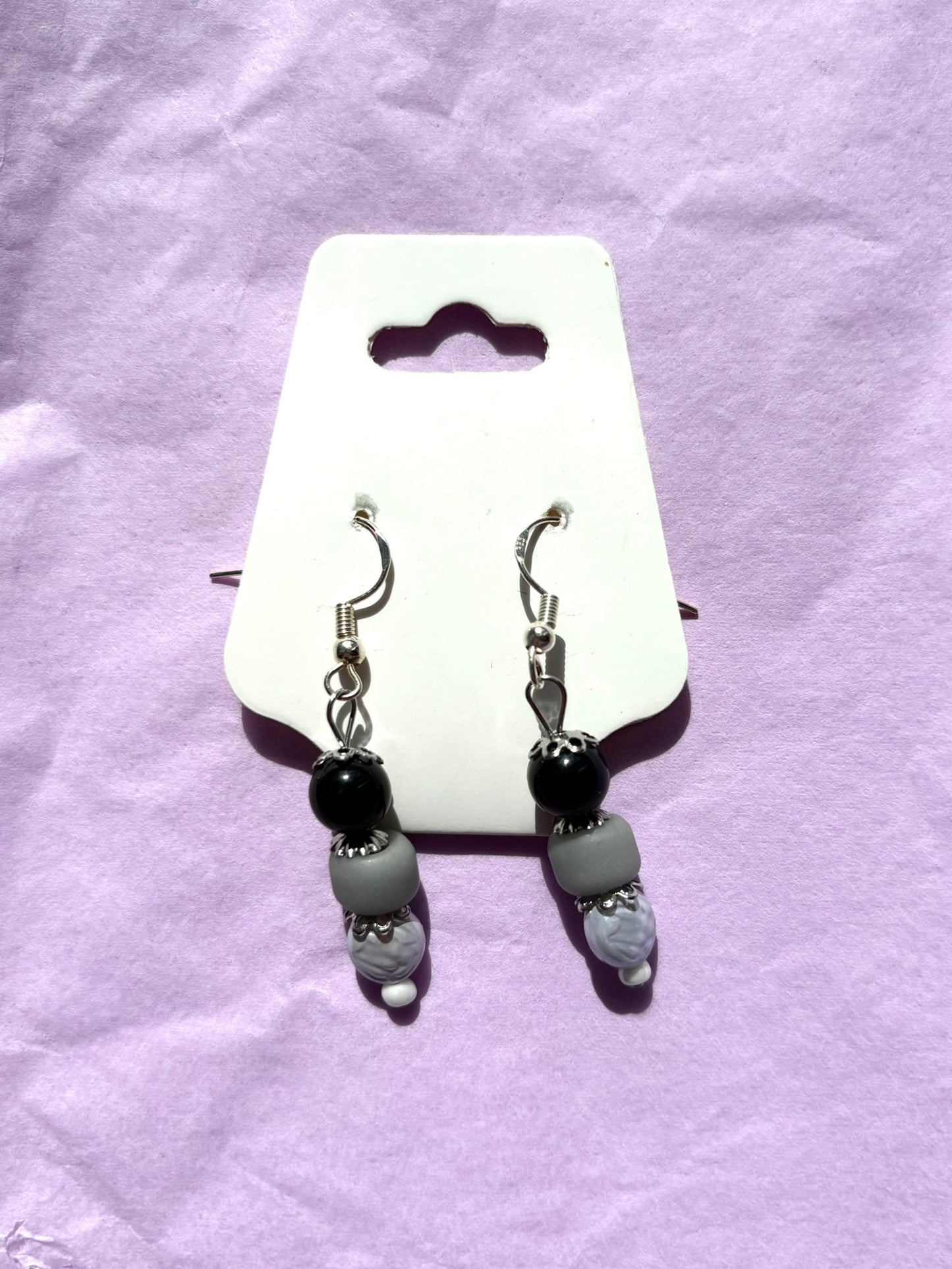 Pair of earrings on a white card with a purple background