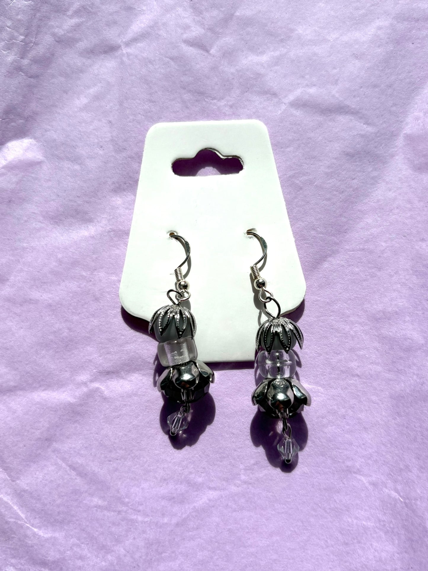 Pair of earrings on a white card with a purple background