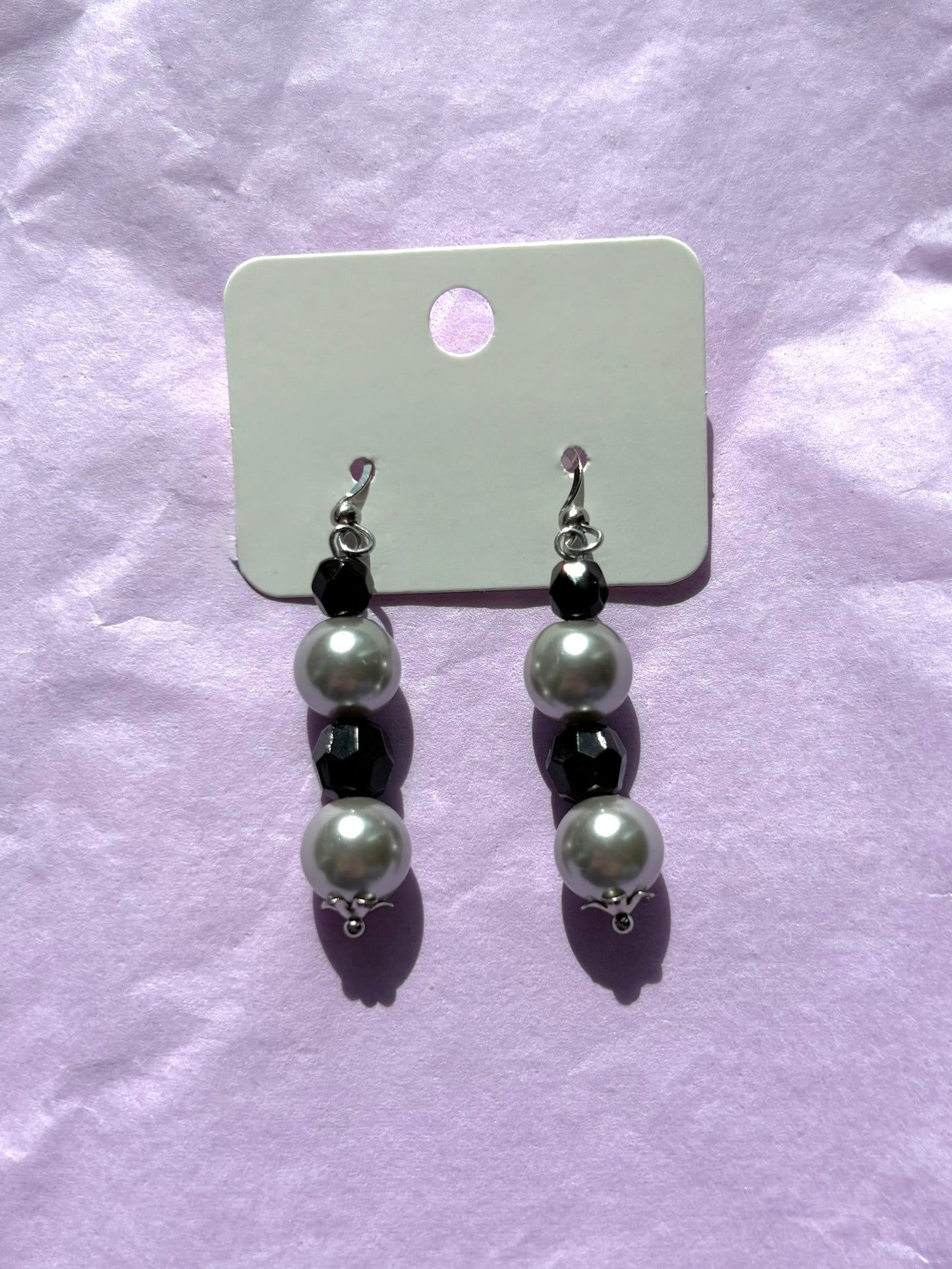 Pair of earrings with grey beads on a purple background