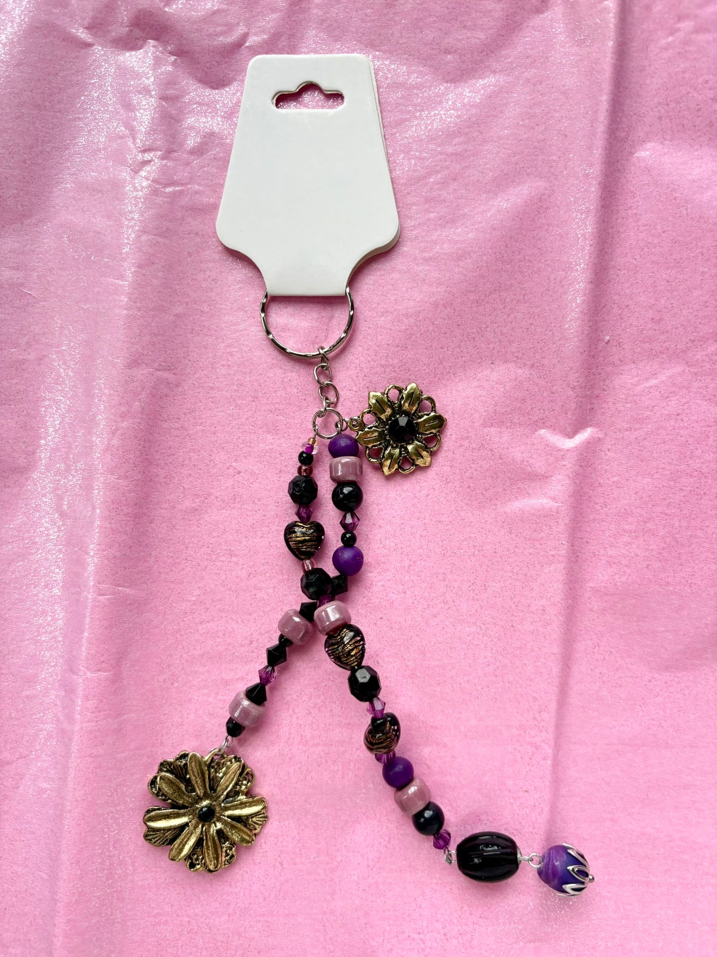 Beaded keychain with floral charms on a pink background