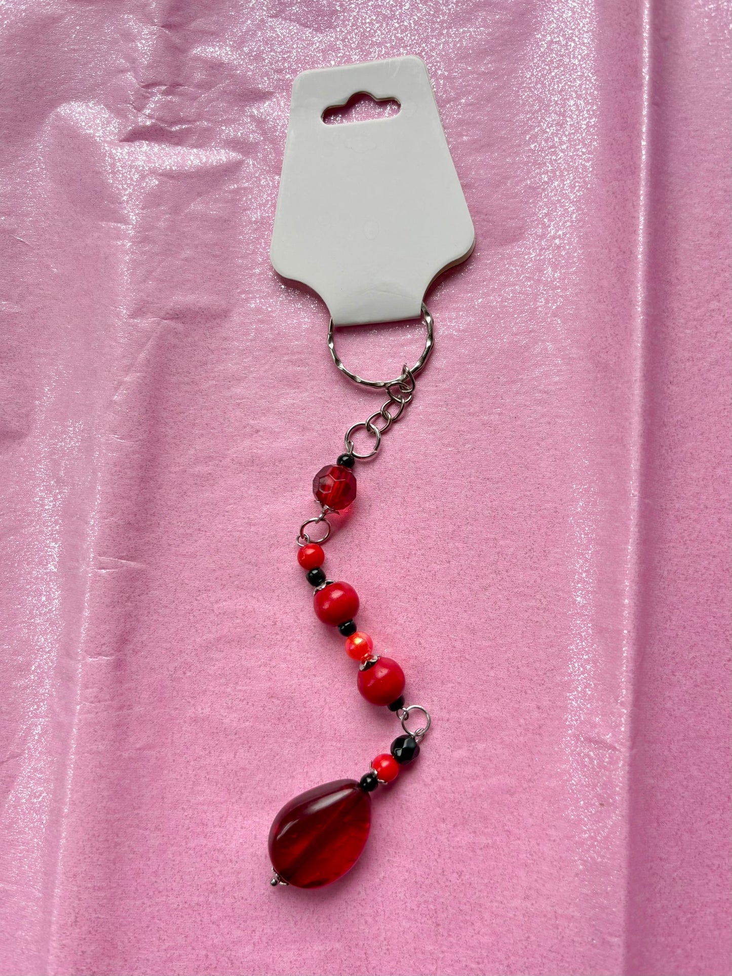Beaded keychain with a teardrop-shaped red pendant on a pink background