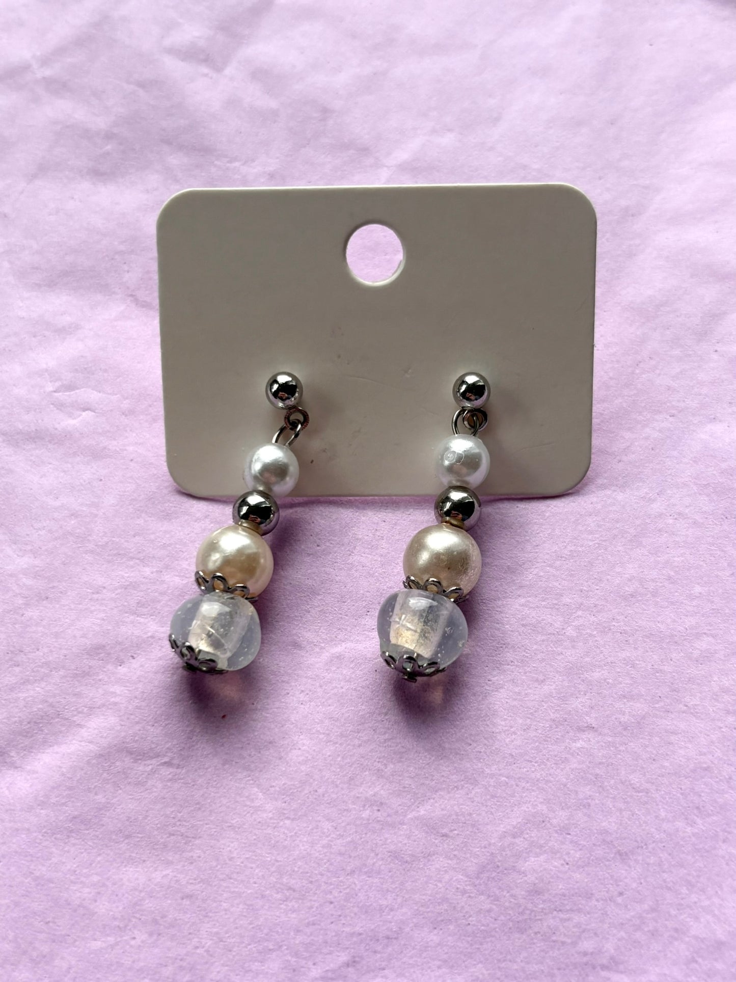 Pair of beaded earrings on a display card against a pink background