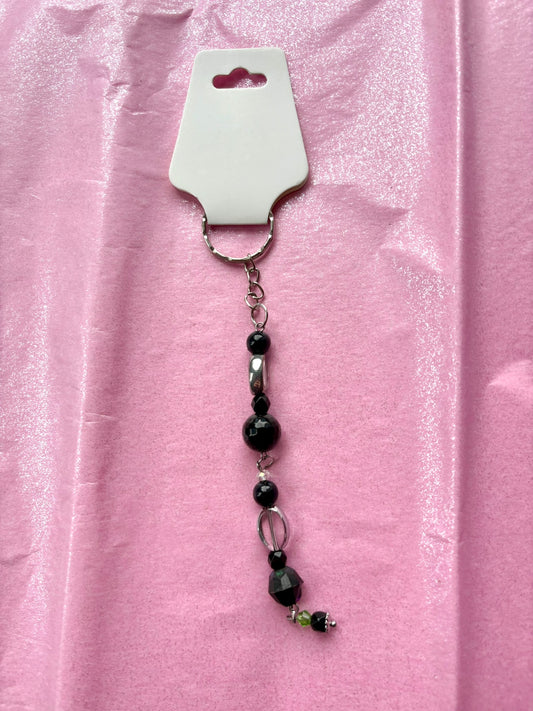 Black beaded keychain on a pink background