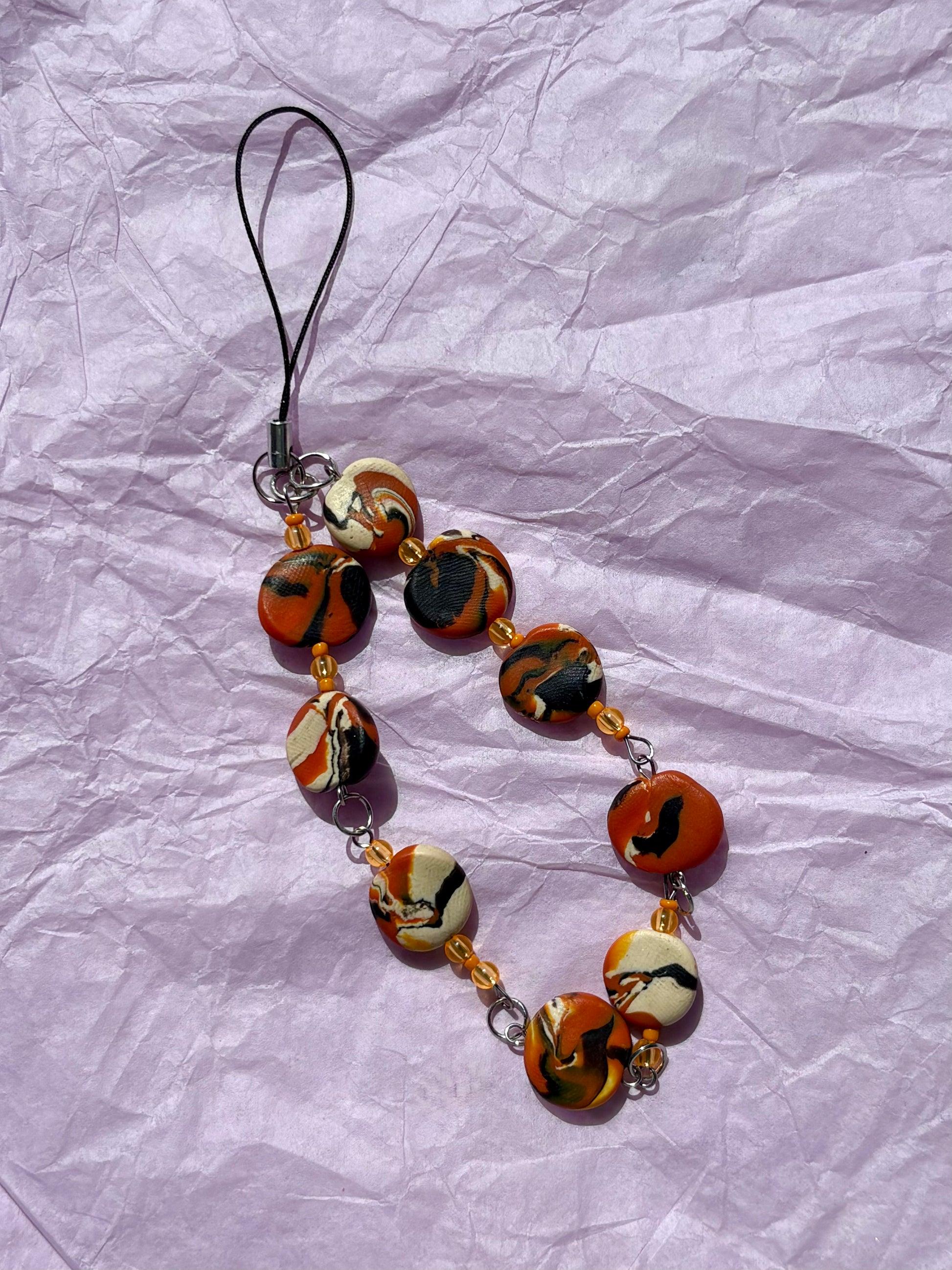 Phone charm with Halloween-themed beads on a crumpled white background