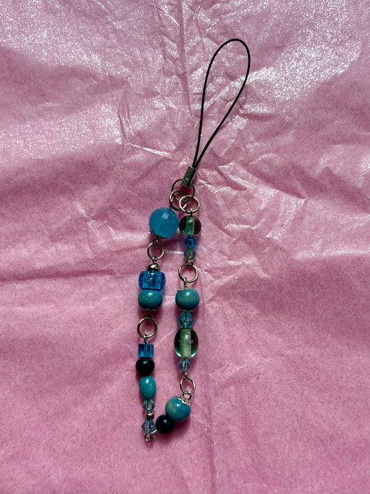 Beaded phone charm on a pink textured background