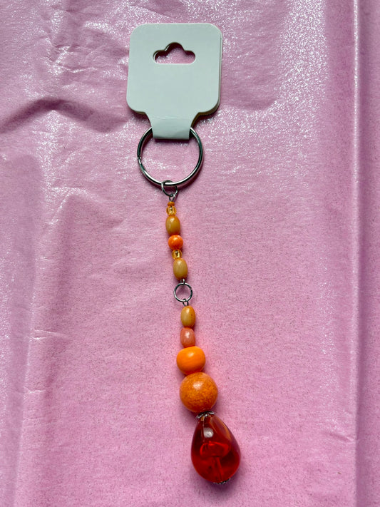 Beaded keychain with a red teardrop bead on a pink background