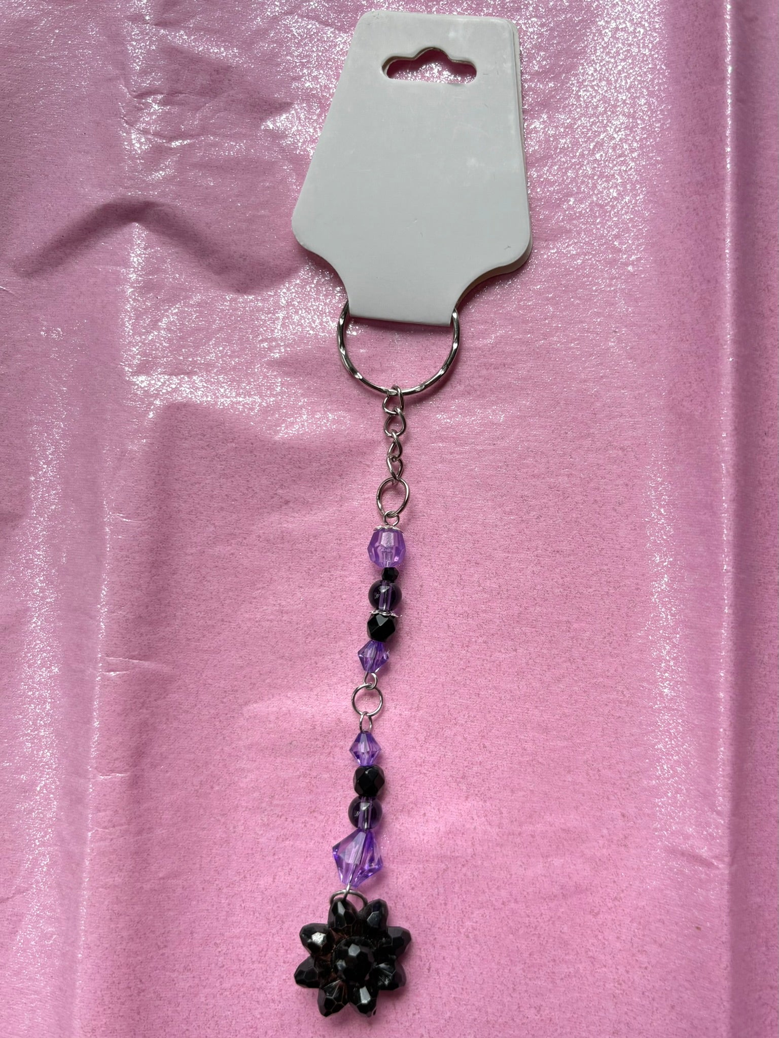 Keychain with beads and a flower charm on a pink background