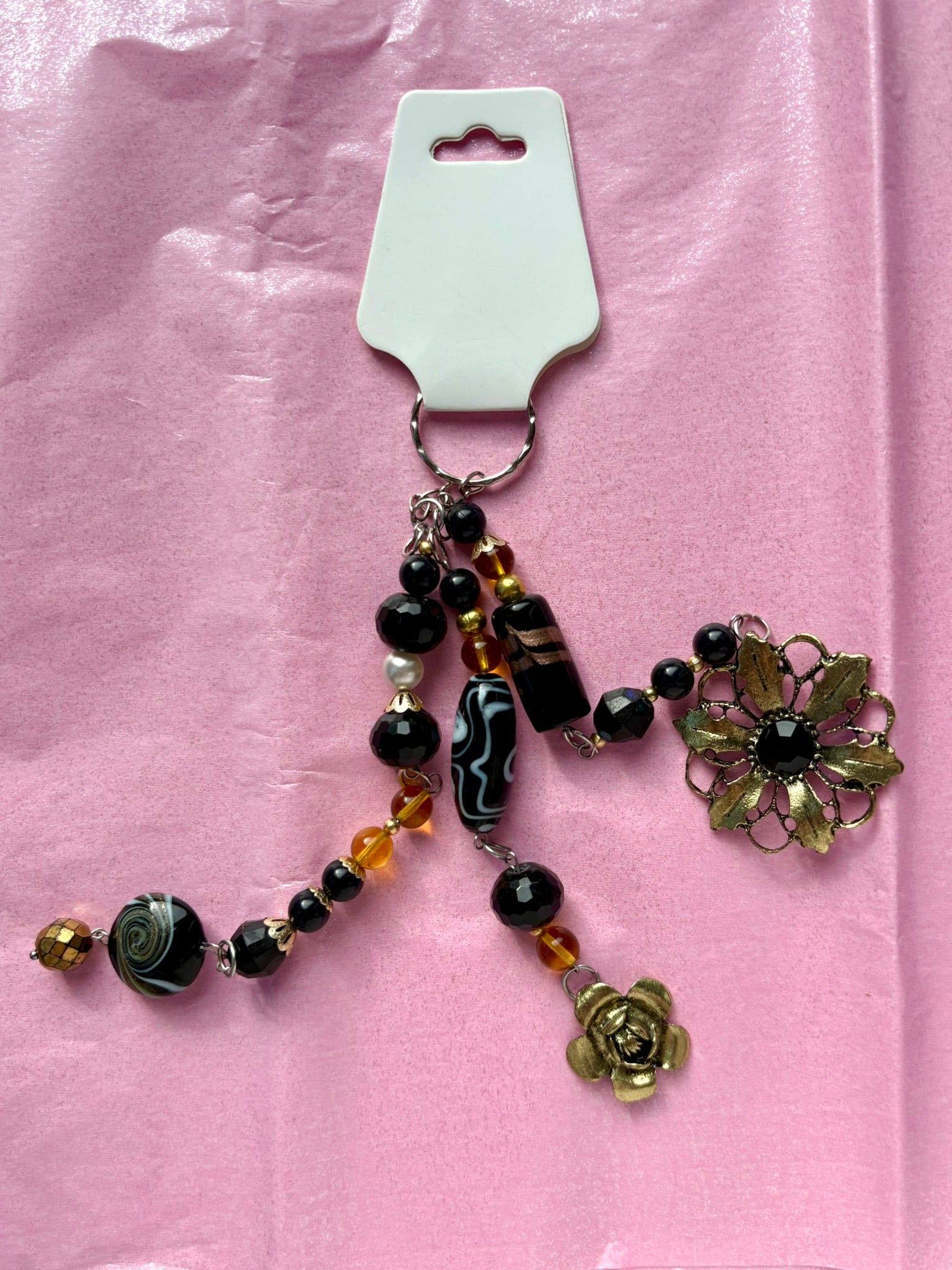 Decorative keychain with beads and floral elements on a pink background