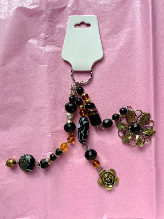 Decorative keychain with beads and floral elements on a pink background