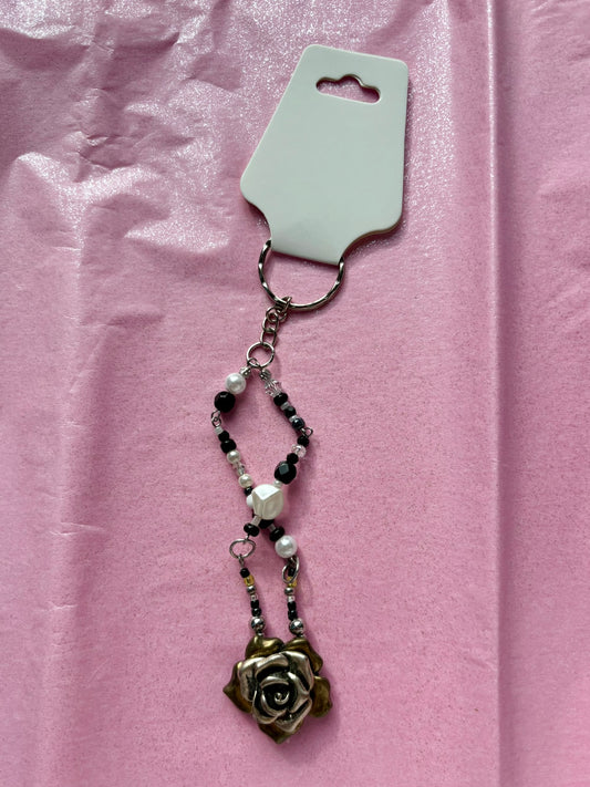 Decorative keychain with rose design on a pink background