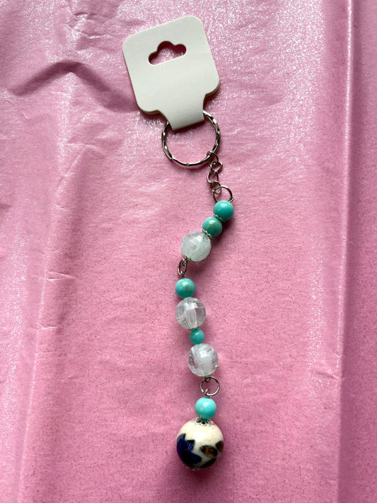 Beaded keychain with a colorful pendant on a pink background
