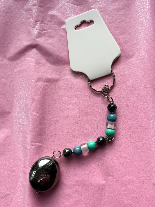 Beaded keychain with a large black bead on a pink background