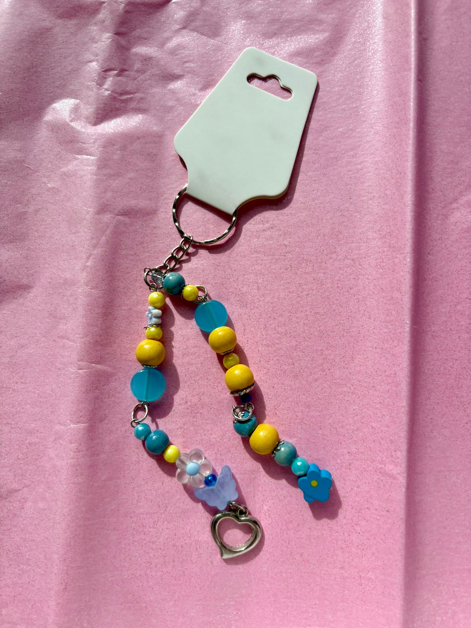 Colorful beaded keychain with a heart charm on a pink background
