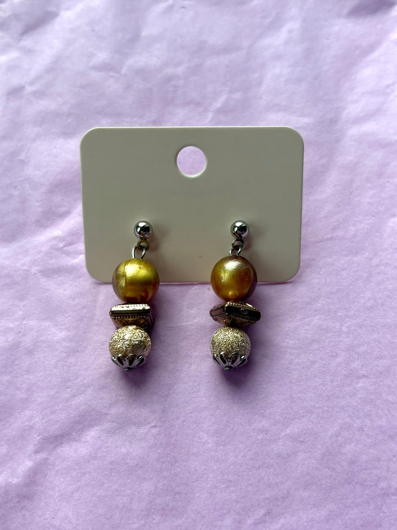 Pair of earrings on a display card against a light purple background