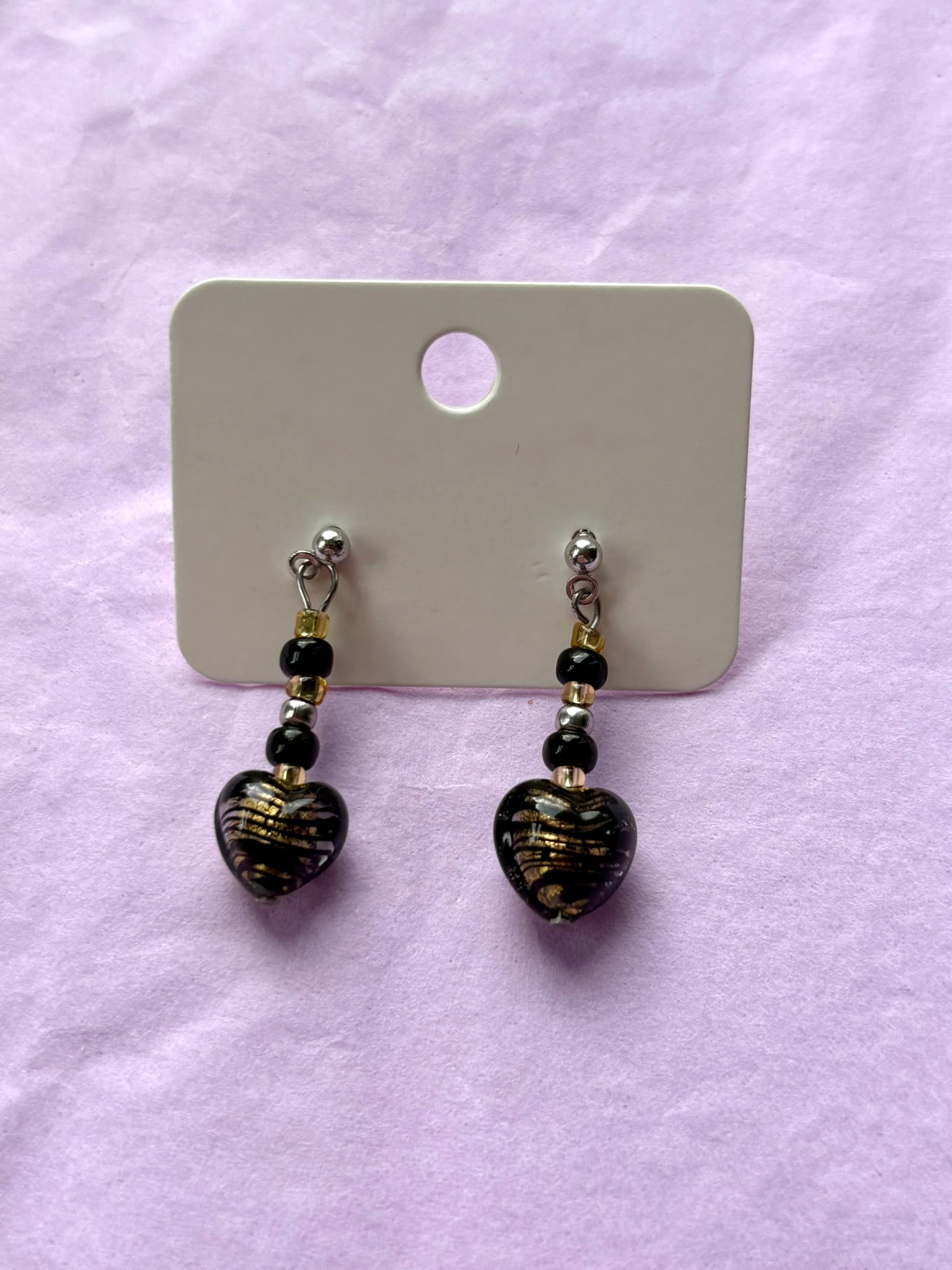 Pair of earrings on a display card with a purple background