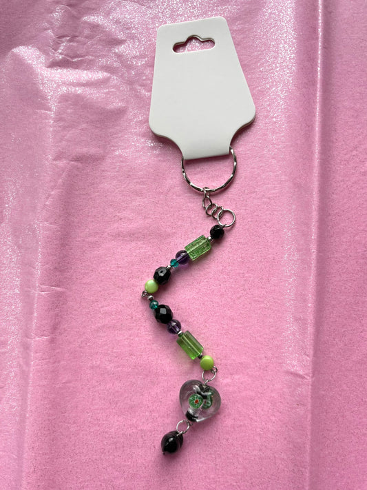 Beaded keychain with a heart charm on a pink background