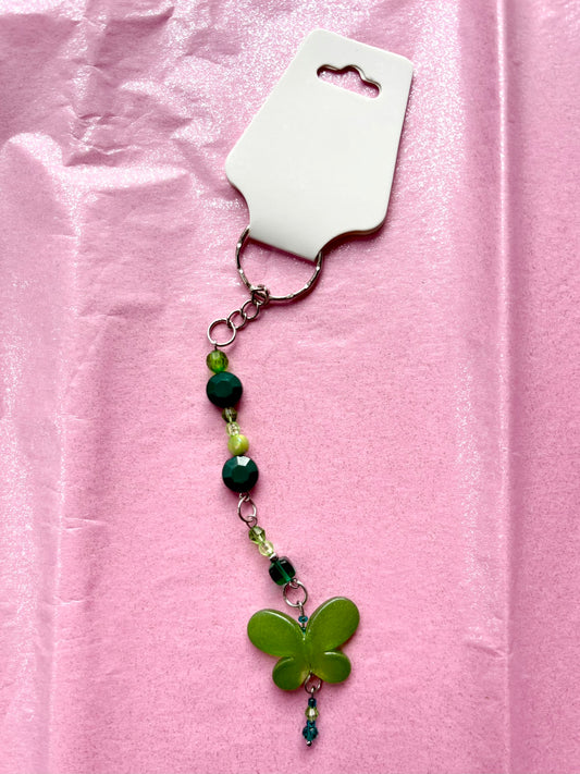 Green butterfly keychain with beads on a pink background