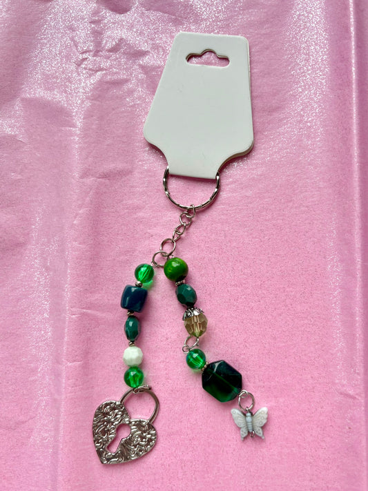 Keychain with green beads and charms on a pink background