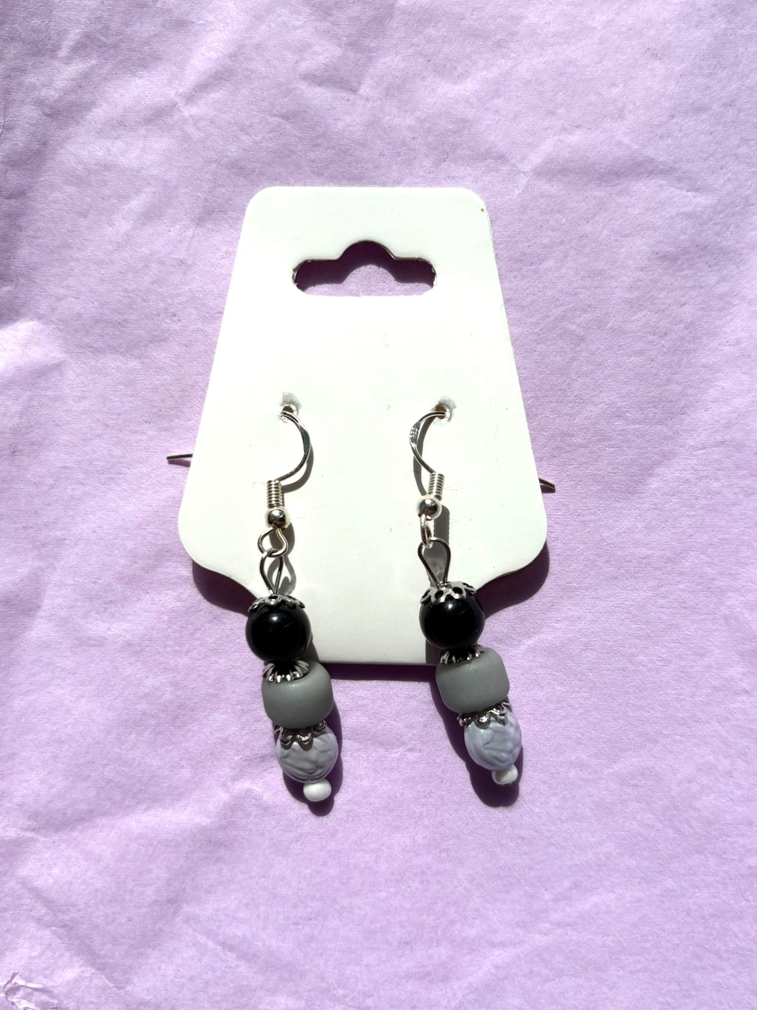 Pair of earrings on a white card with a purple background