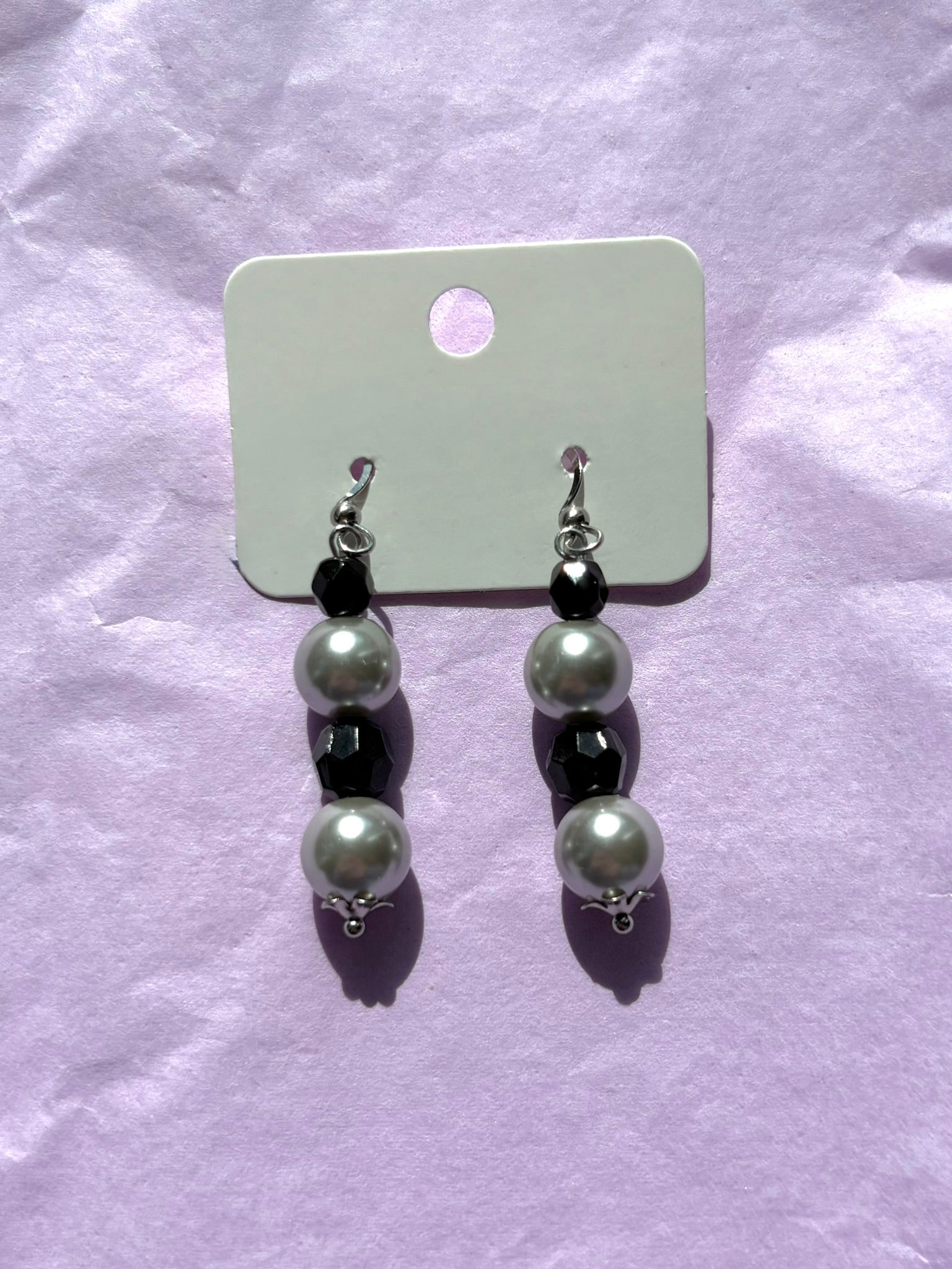 Pair of earrings with grey beads on a purple background