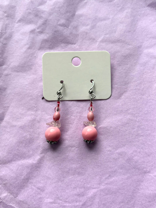 Pair of pink beaded earrings on a light purple fabric background