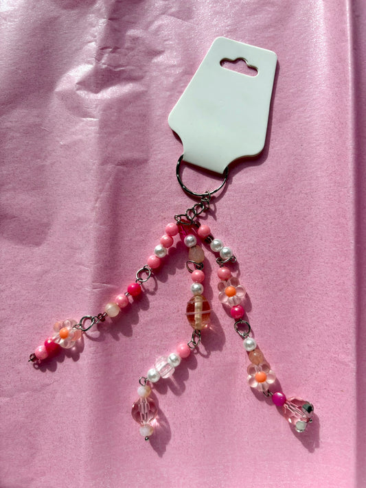 Beaded keychain on a pink card against a pink fabric background