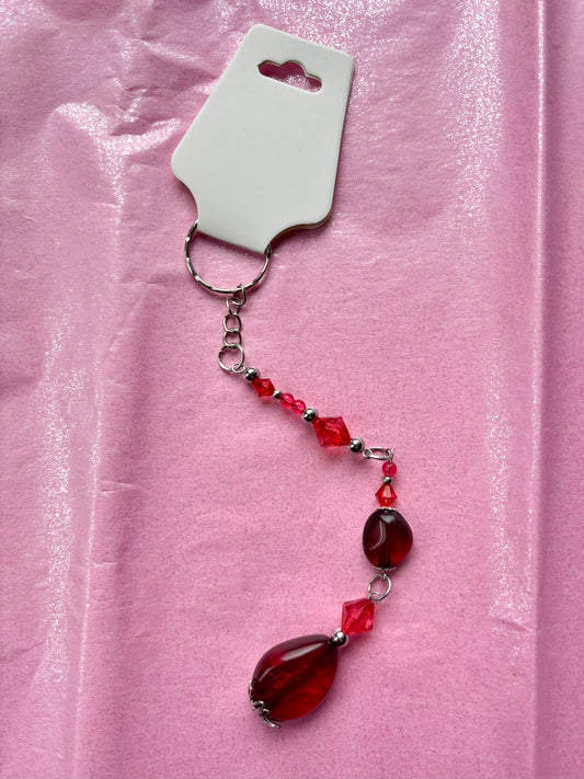Beaded keychain with red and clear beads on a pink fabric background