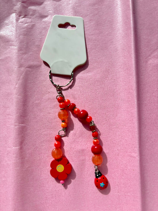 Beaded keychain with red flowers on a pink background